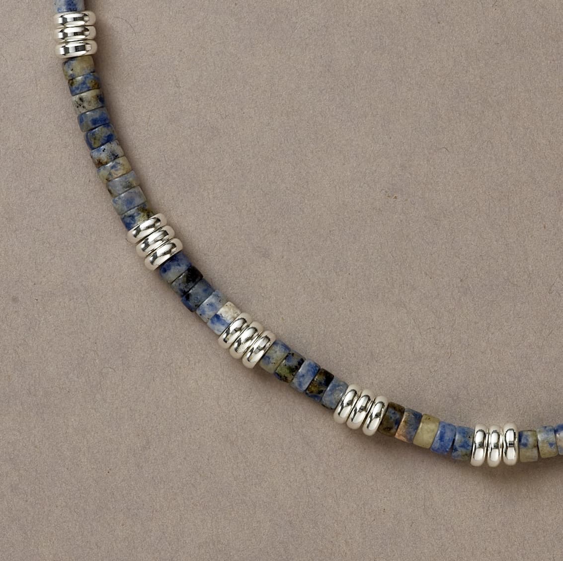 Close-up of Blue Mind necklace showcasing Sodalite beads and silver accents in a gentle curve on neutral background.
