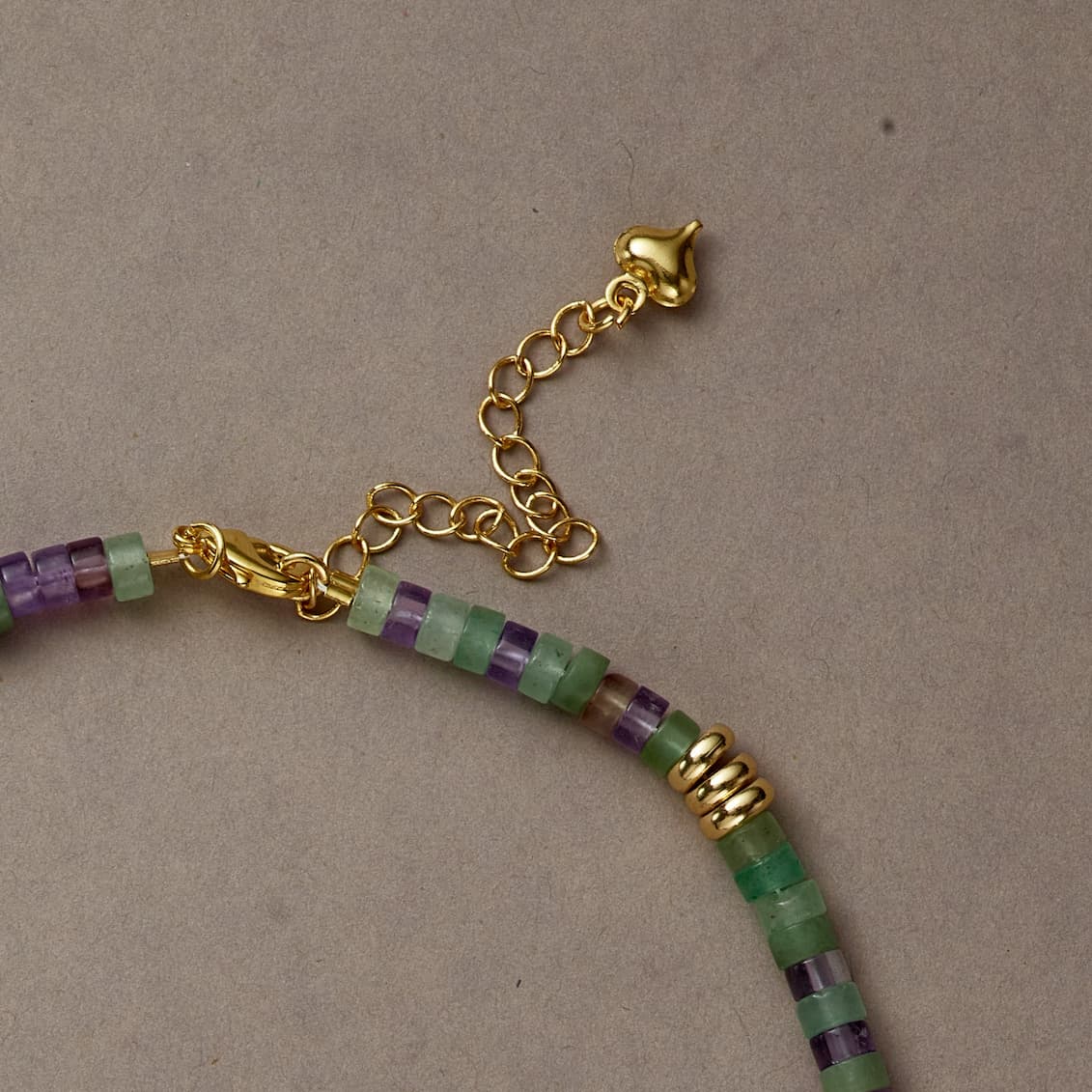 Side view of Earth & Spirit necklace highlighting green and purple stones with a gold clasp detail.