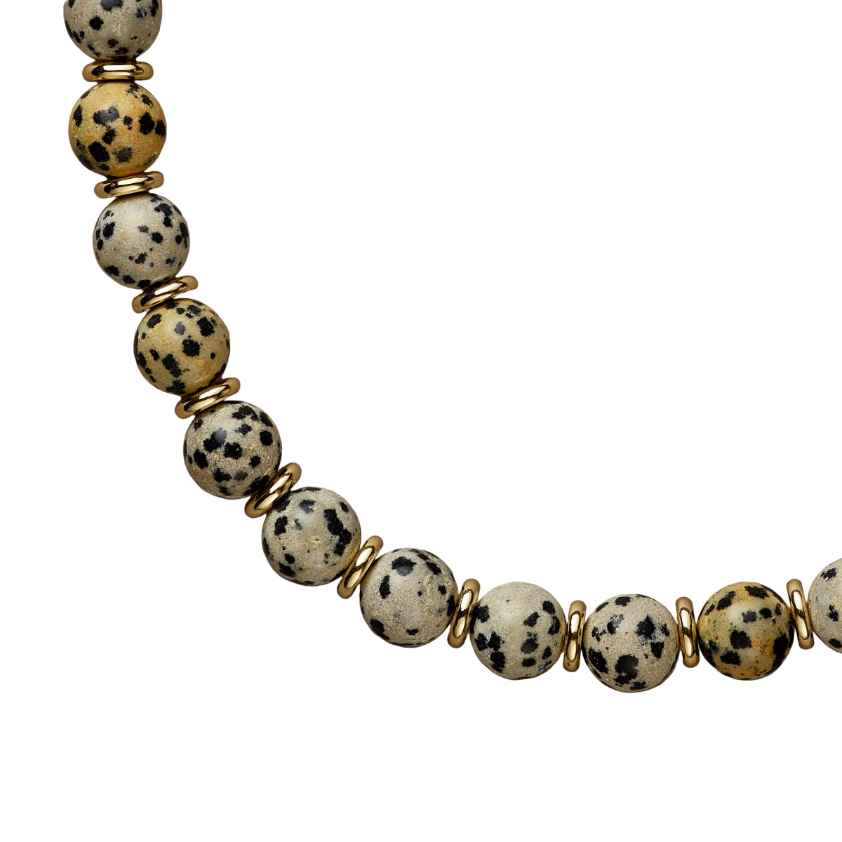 Necklace with dalmatian jasper beads and gold accents on a beige background