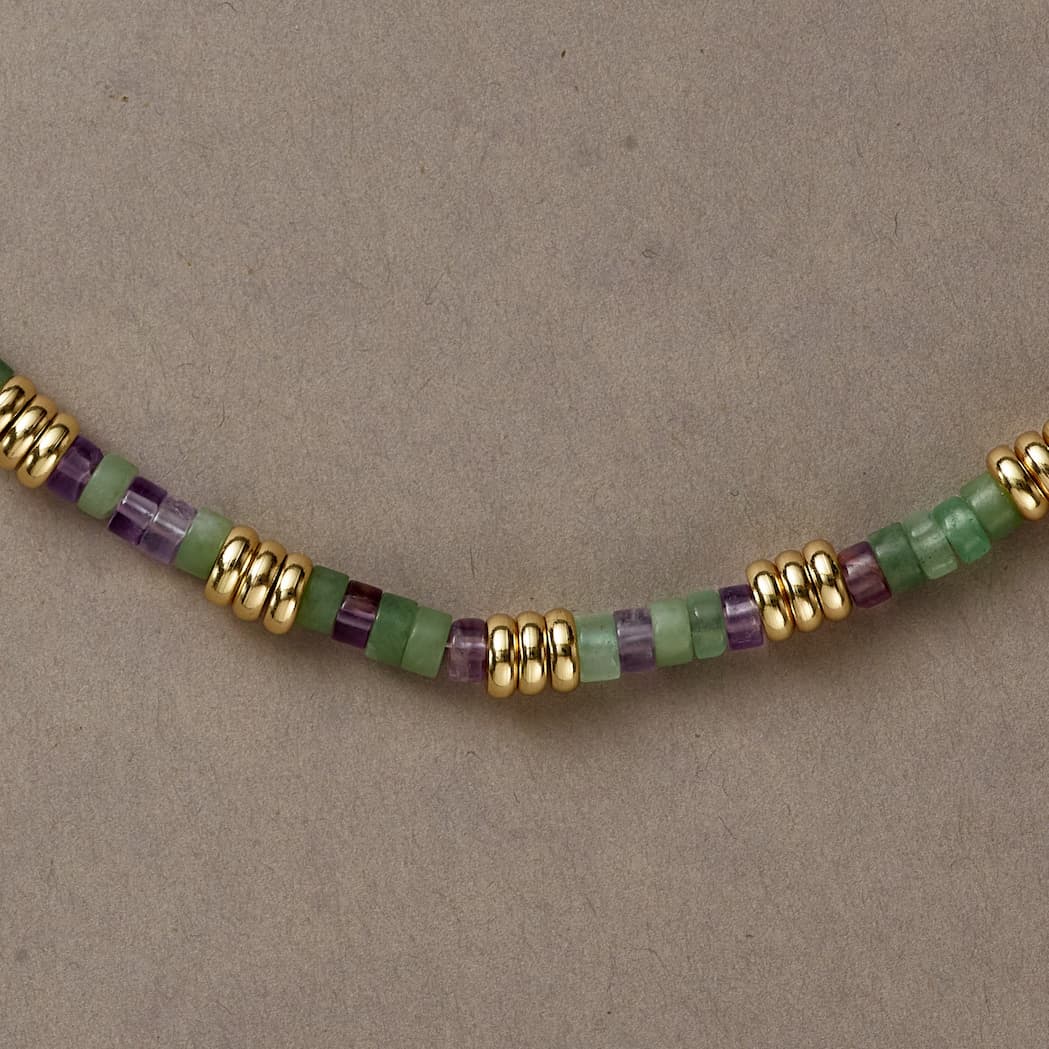 Macro shot of Earth & Spirit necklace featuring polished beads in green and violet tones with metallic spacers.