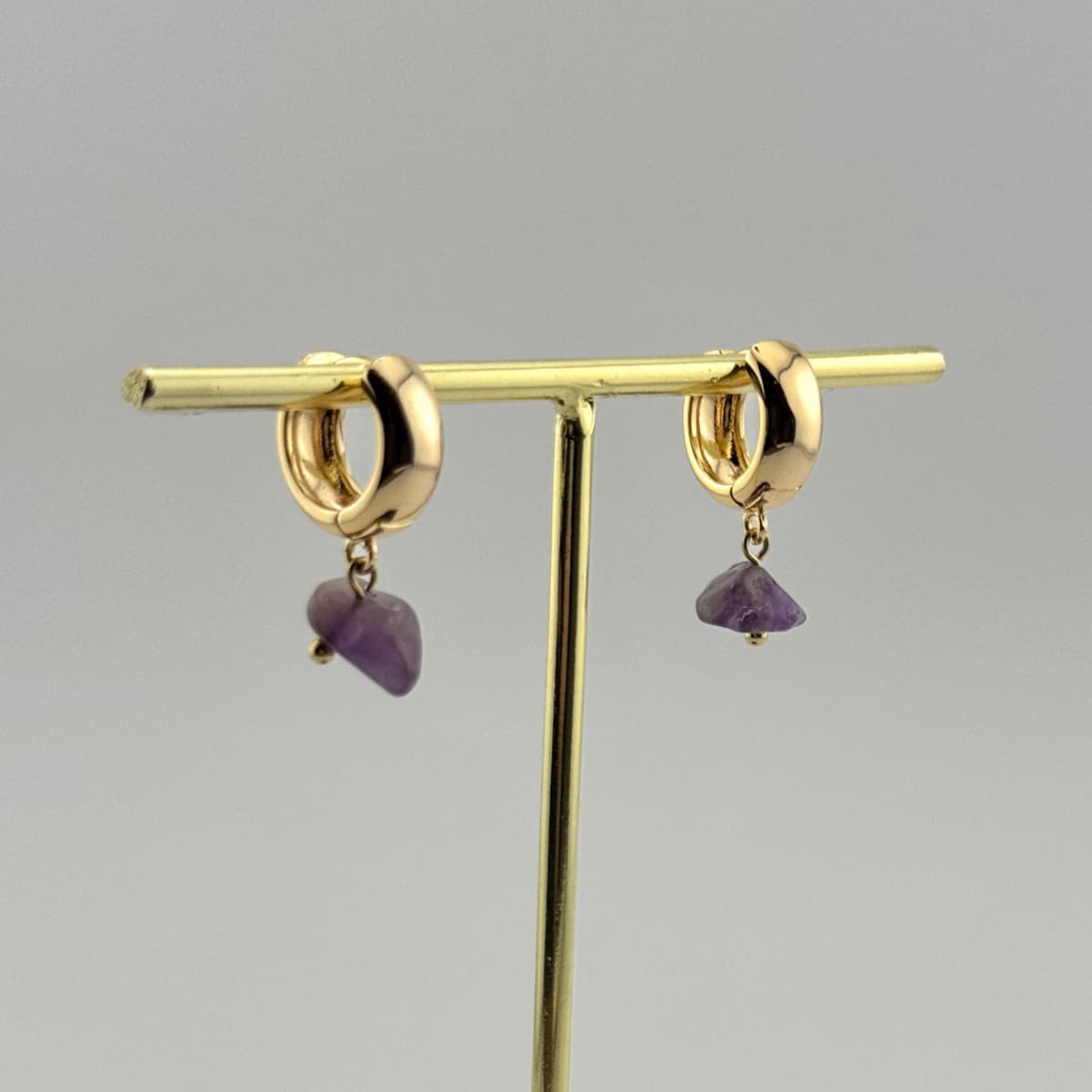 Gold earrings with purple stones on a gray background