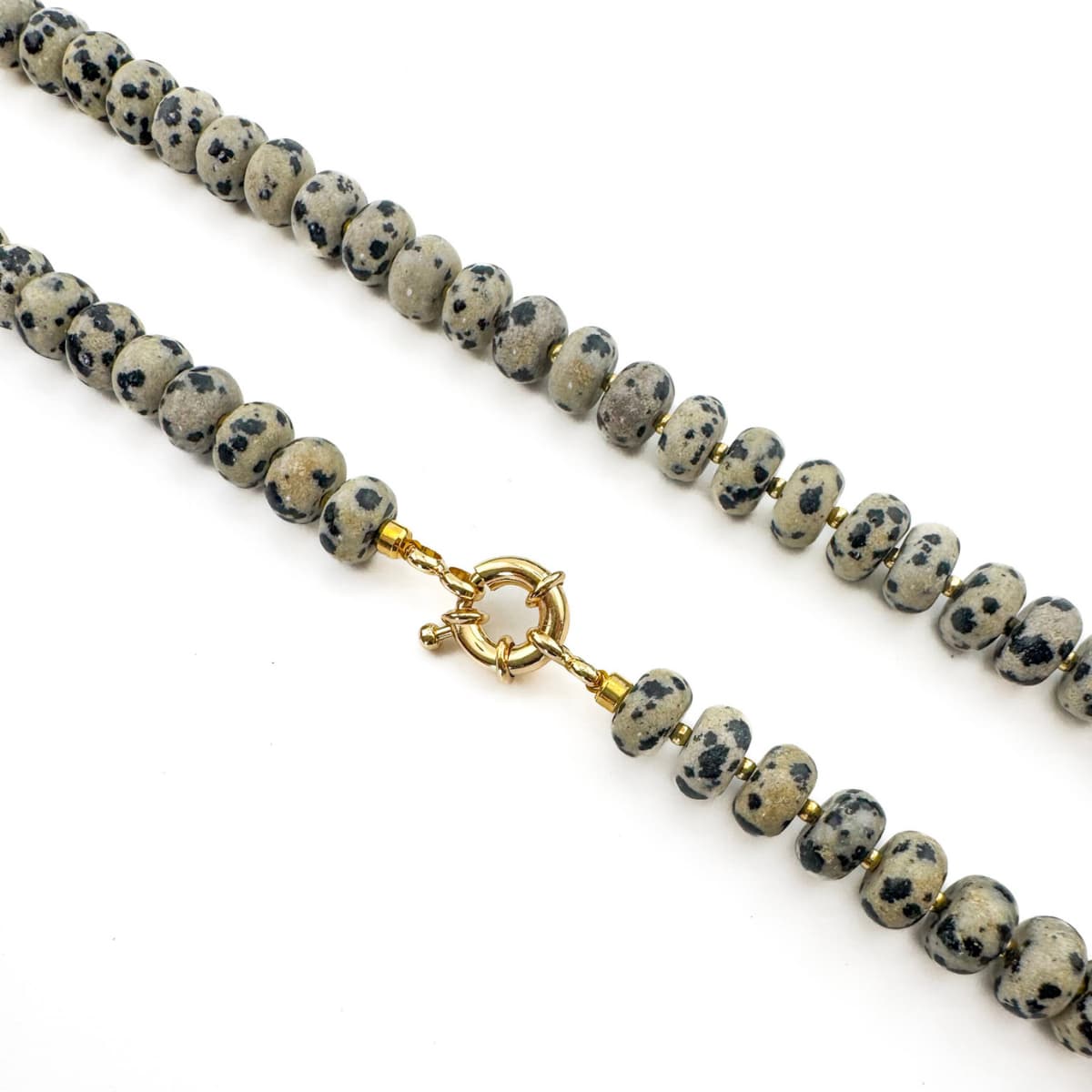 Necklace with dalmatian jasper beads and a gold clasp on a white background