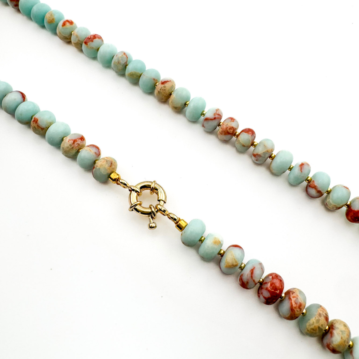Necklace with turquoise and red beads and a gold clasp on a white background