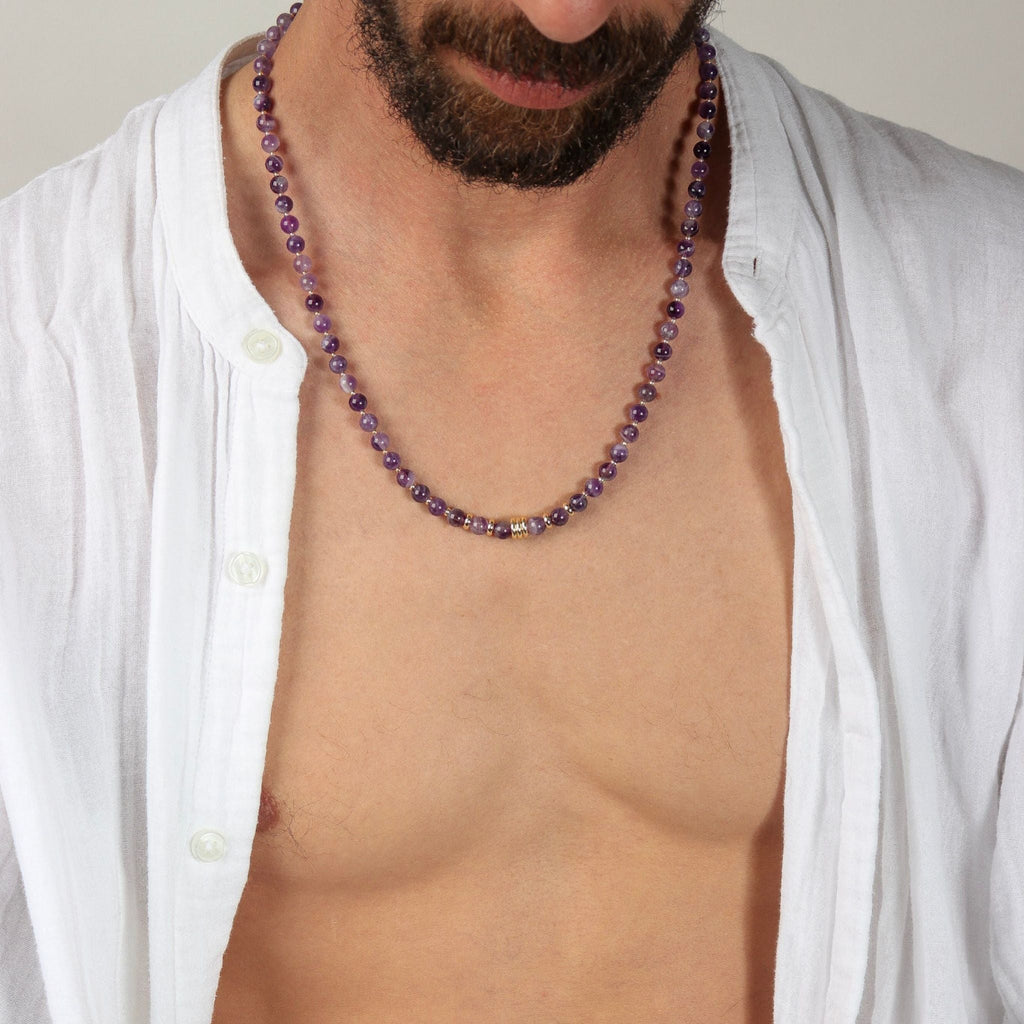 Man wearing a purple beaded necklace with a white shirt open
