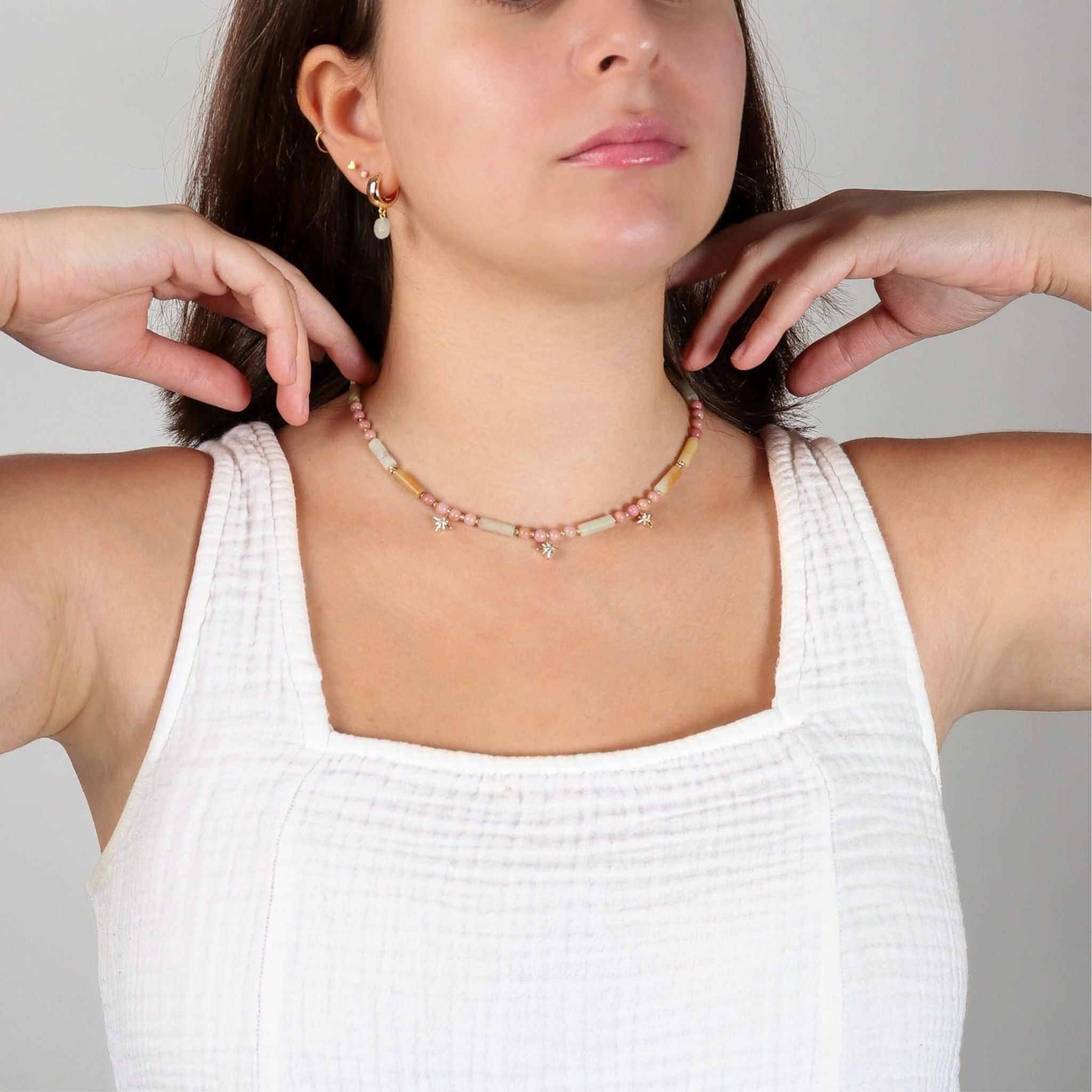 Woman wearing a beaded necklace with a neutral background