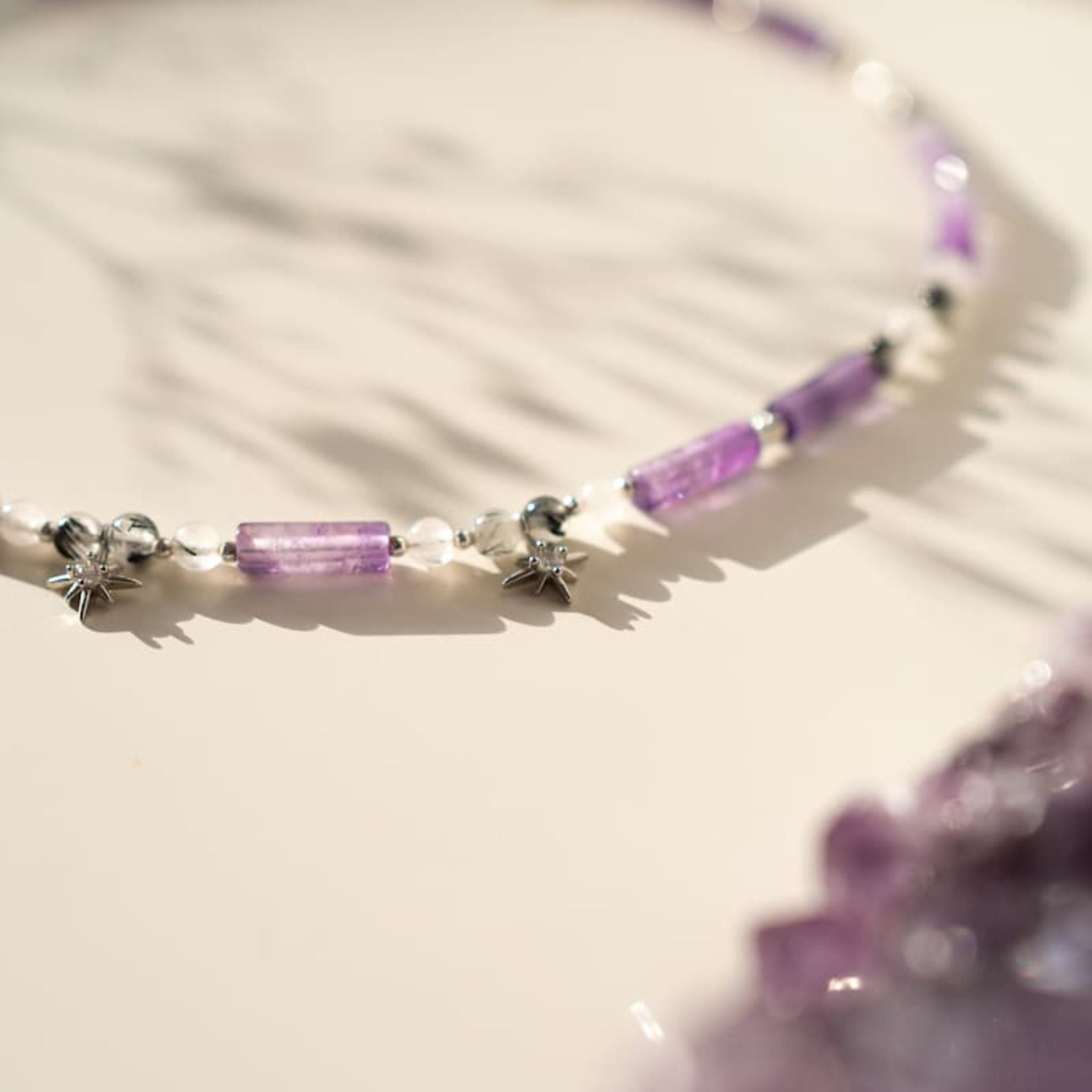 Necklace with purple beads and star-shaped clasps on a light background