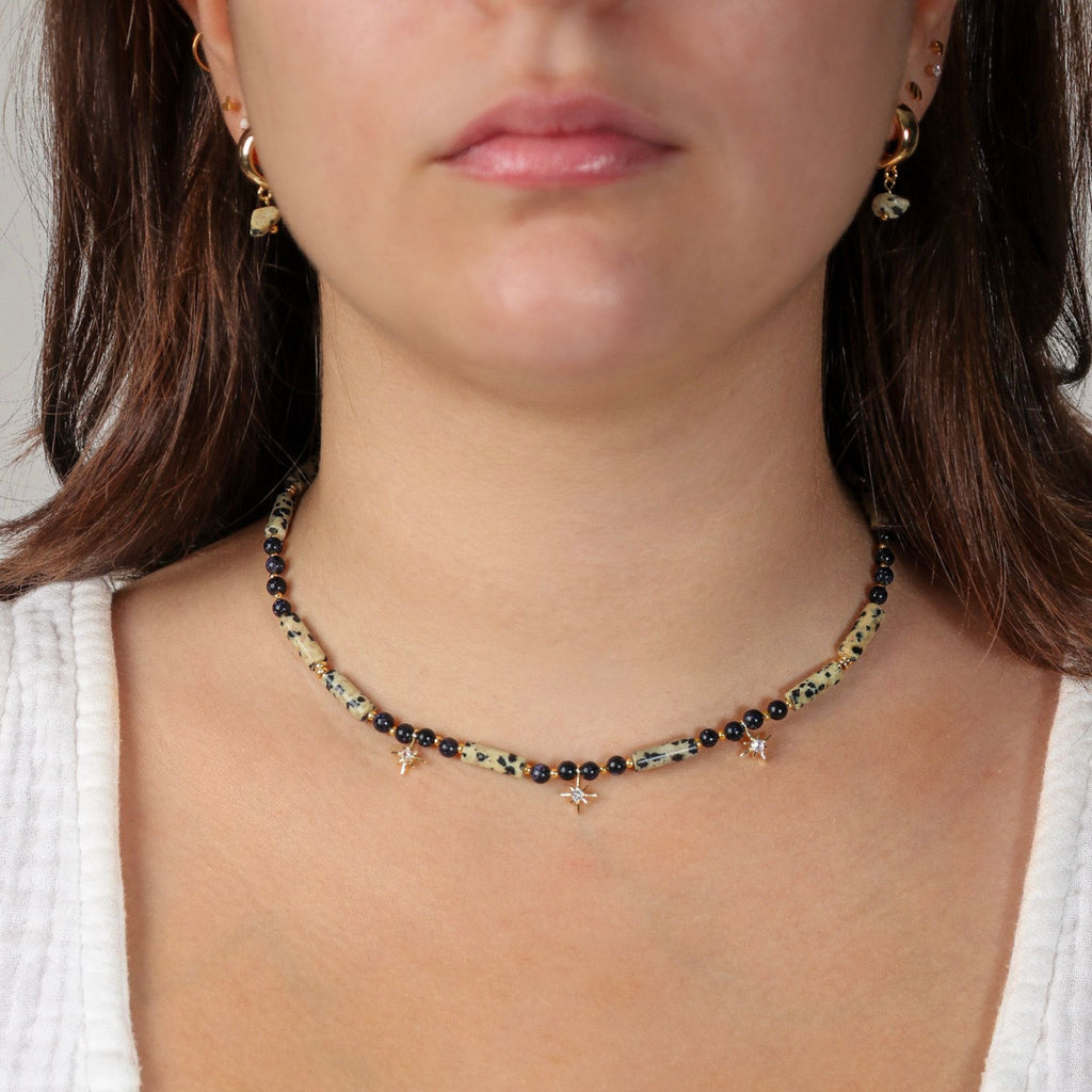 Necklace with black and gold beads worn by a person on a neutral background