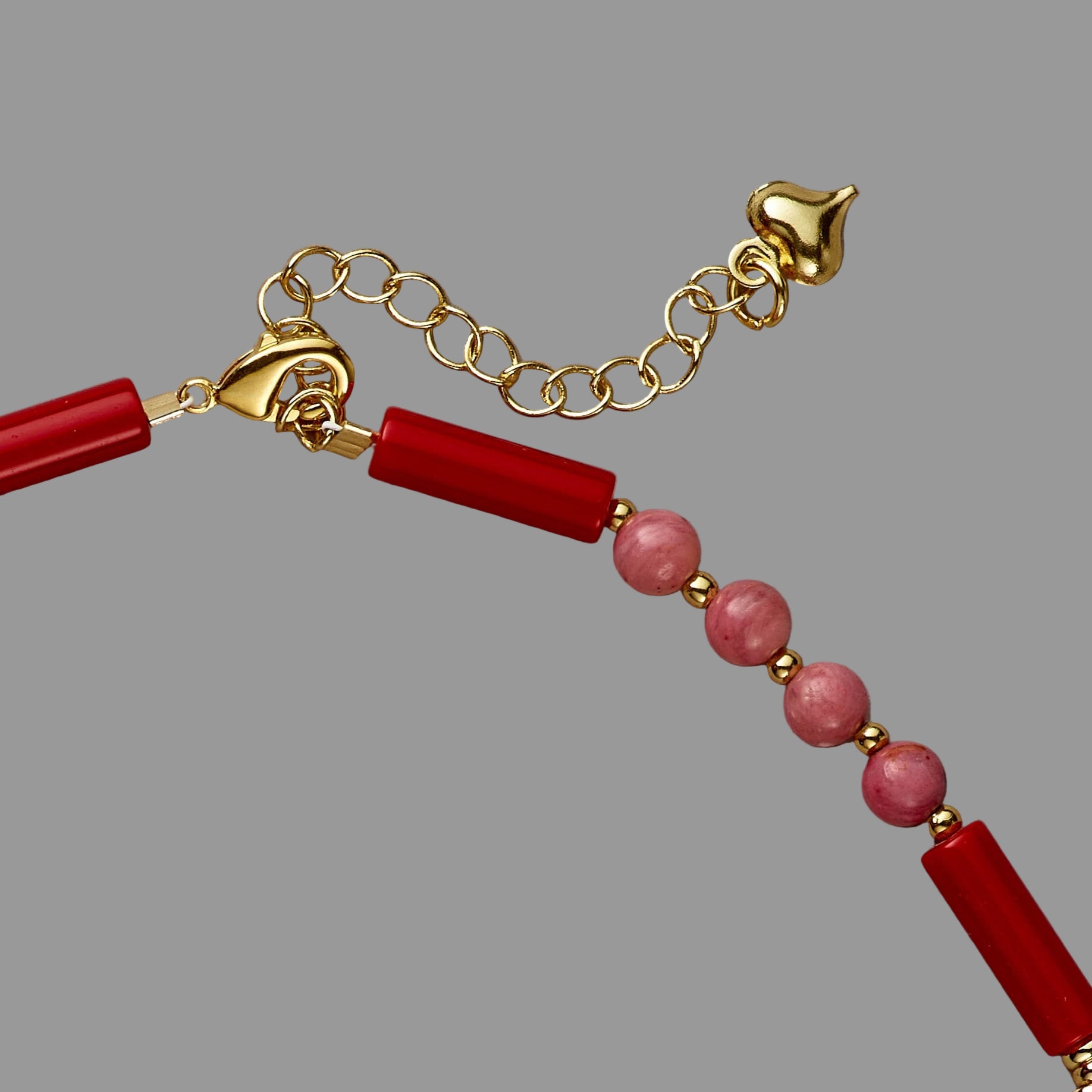 Bracelet with red beads and gold chain on a beige background