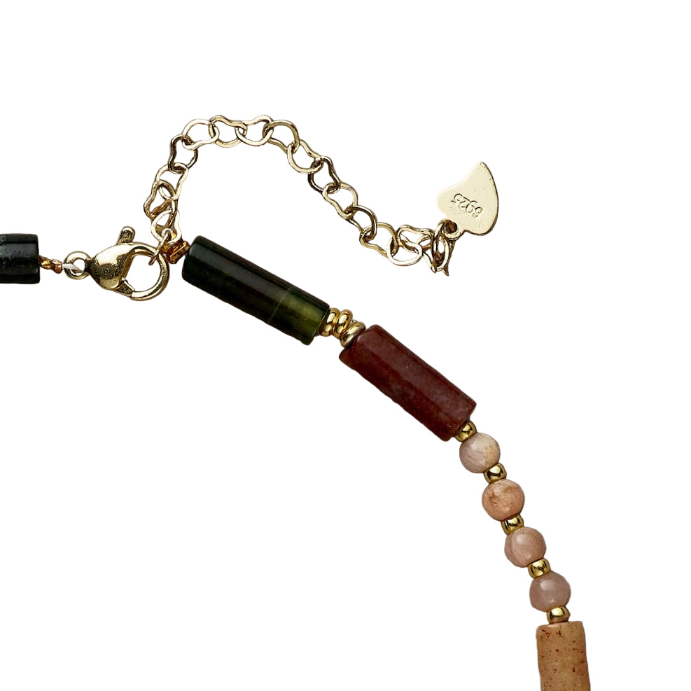 Close-up of a beaded necklace with gold chain and clasp on a beige background