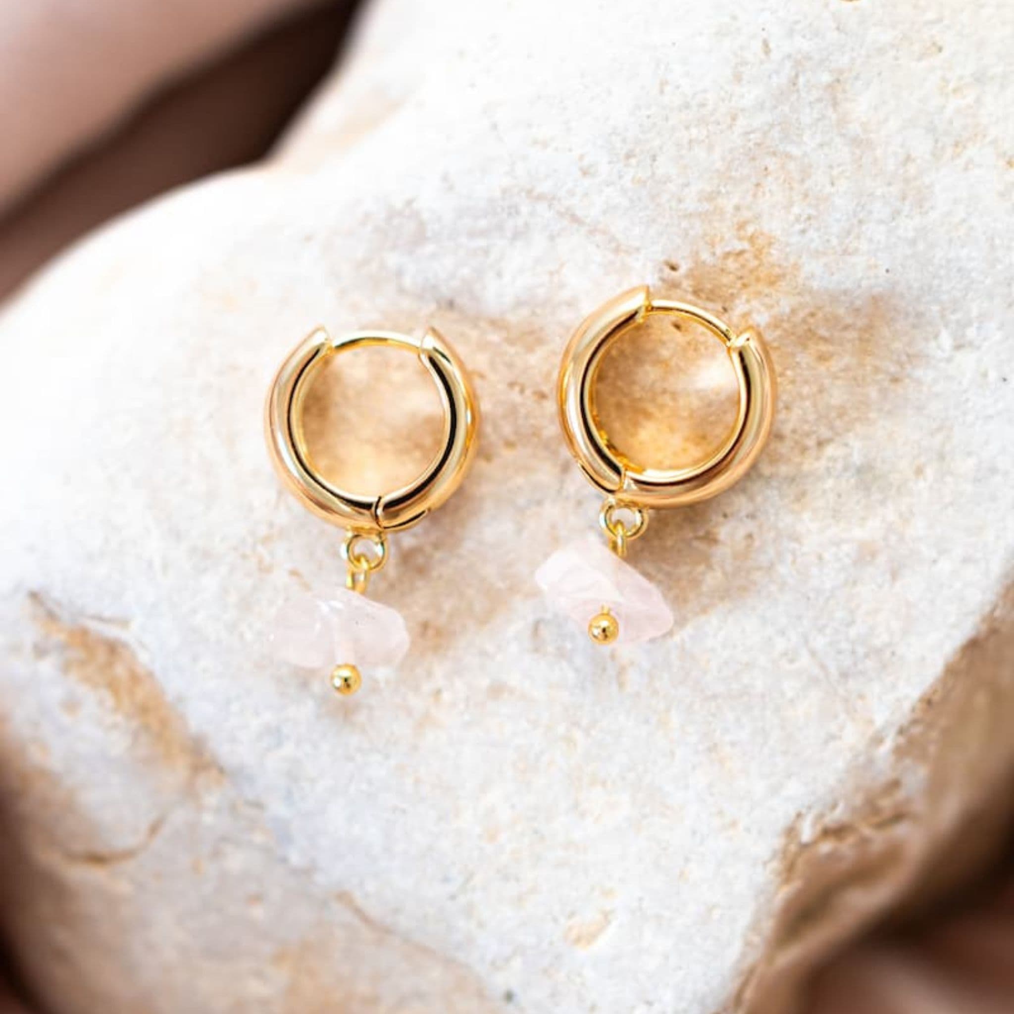 Gold hoop earrings on a textured beige surface