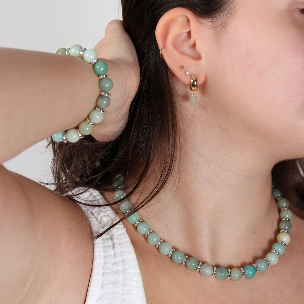Close-up of a person wearing a turquoise beaded necklace and earring set.