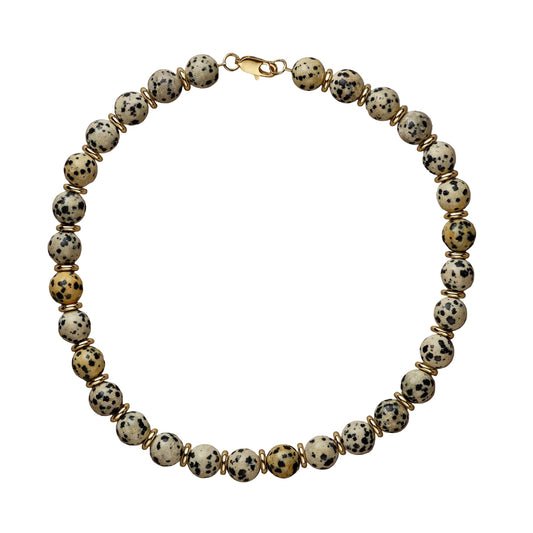 Bracelet with dalmatian jasper and gold beads on a beige background