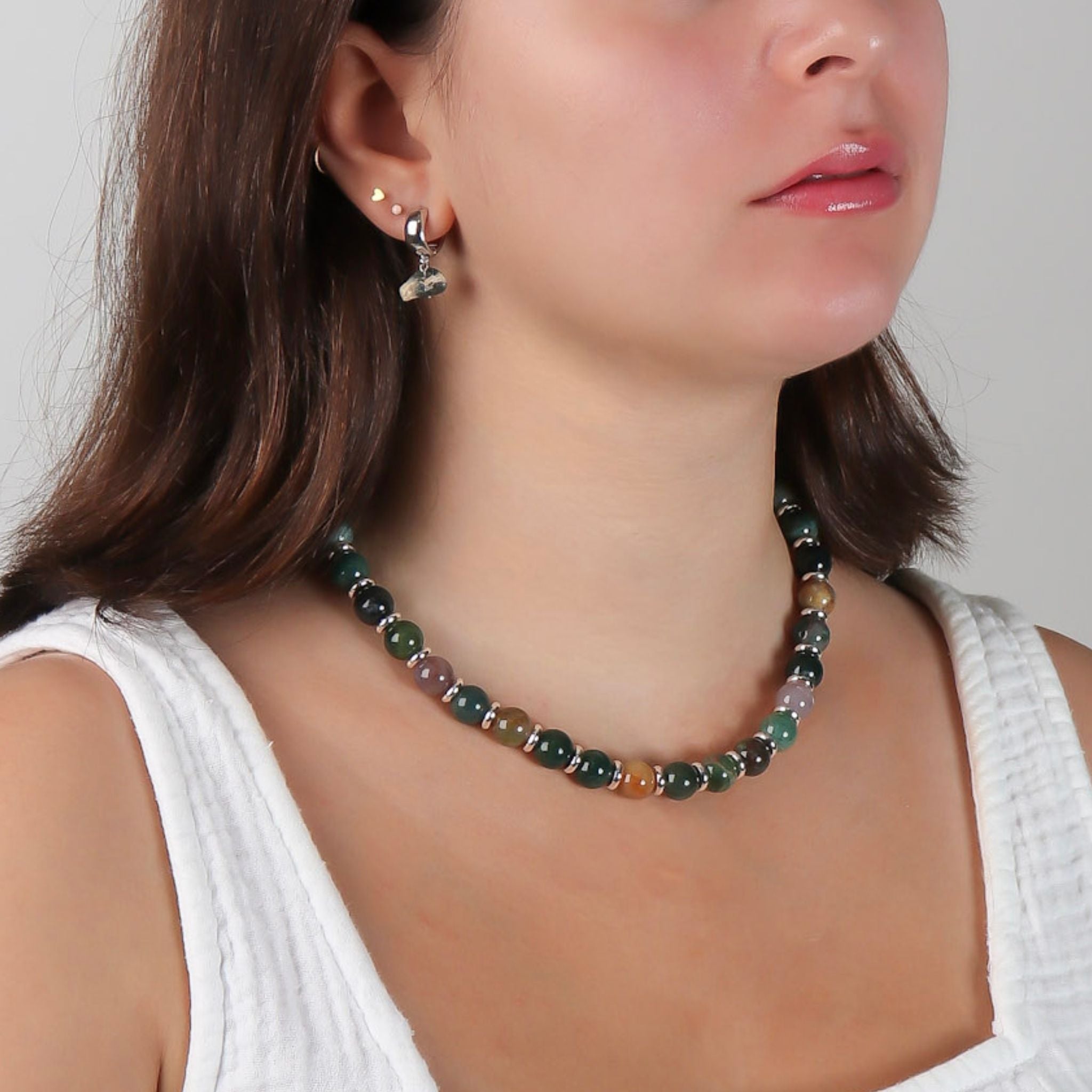 Woman wearing a beaded necklace and earrings on a plain background