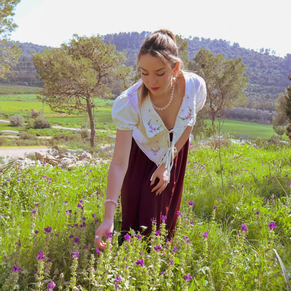Woman standing in a field of flowers with a scenic background