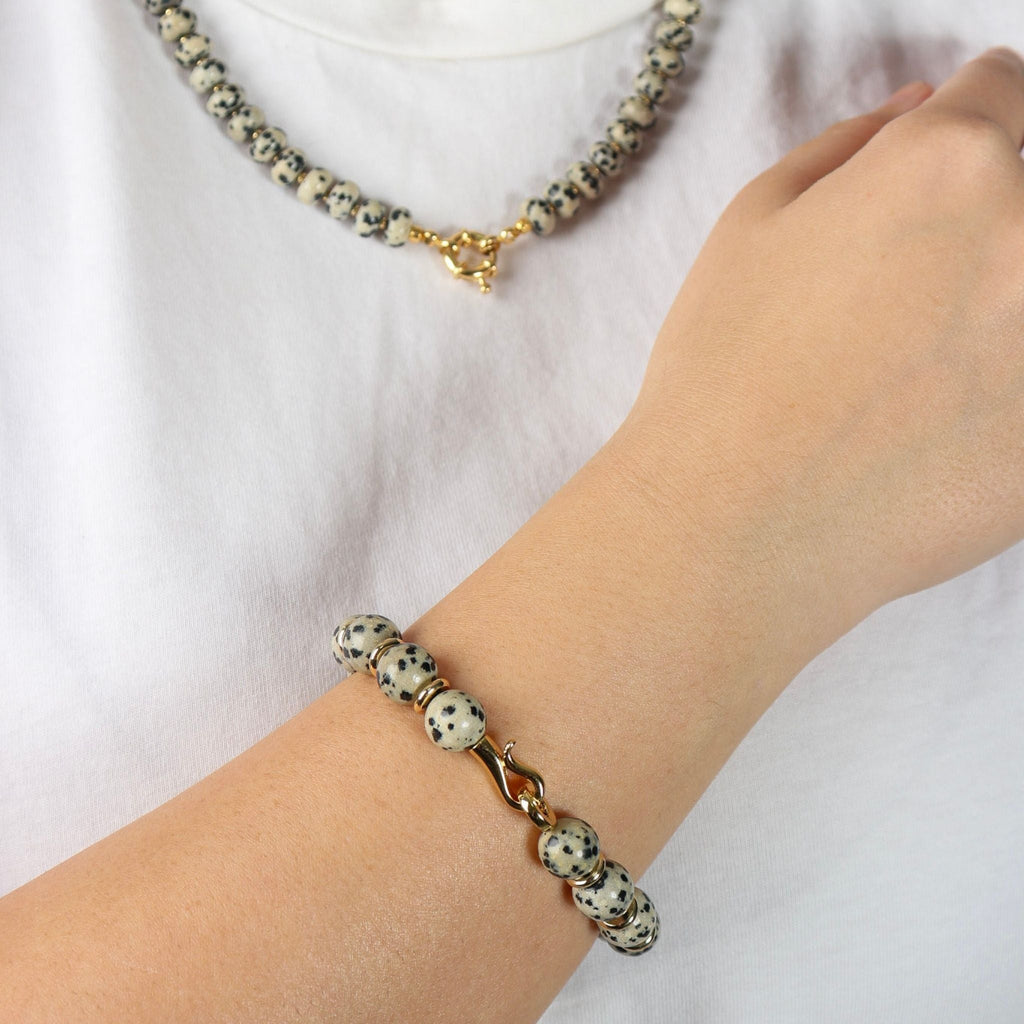 Bracelet with dalmatian jasper beads on a wrist against a white background