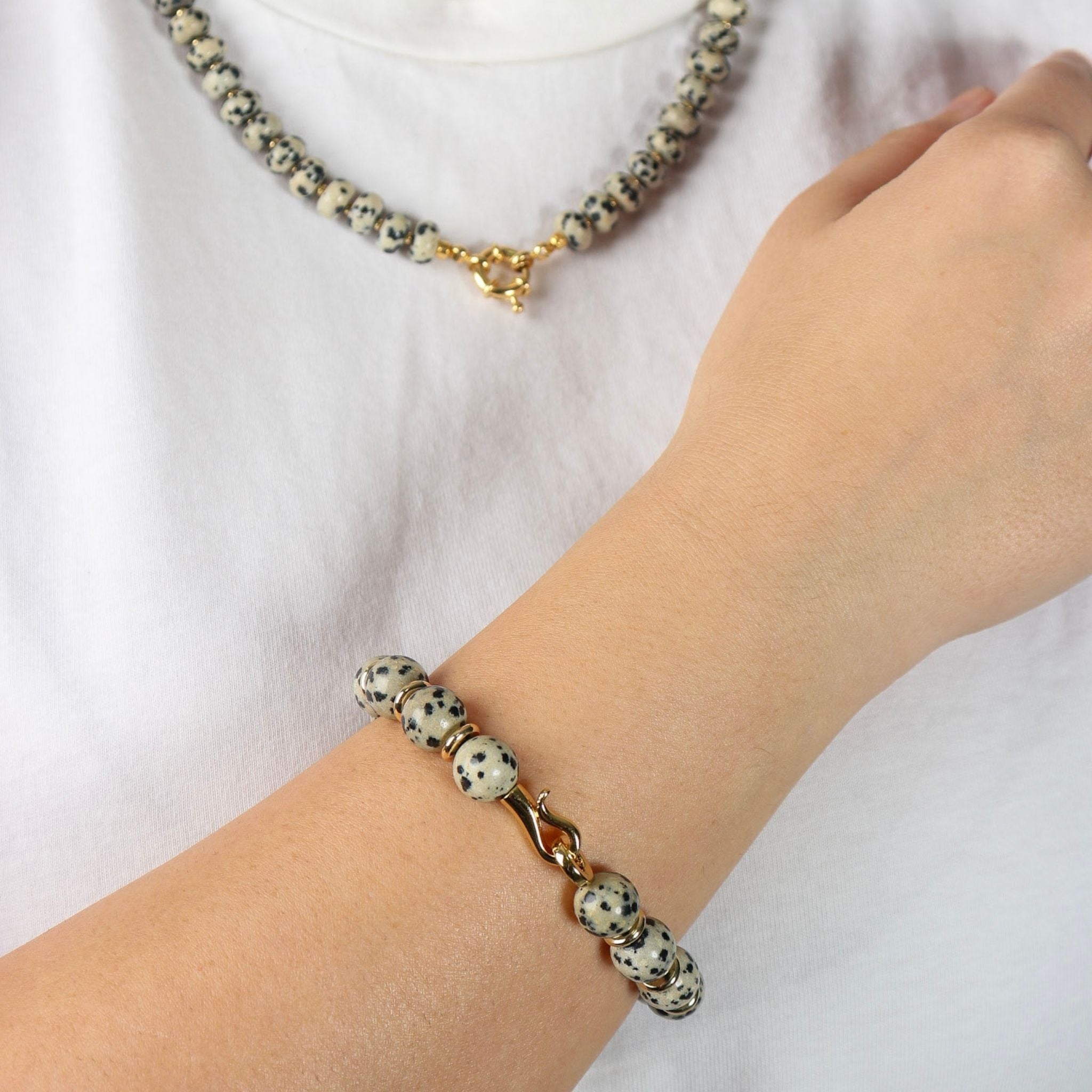 Bracelet with dalmatian jasper beads on a wrist against a white background